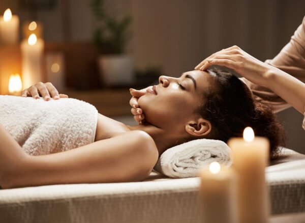 Attractive african girl enjoying face massage in spa salon. Closed eyes.