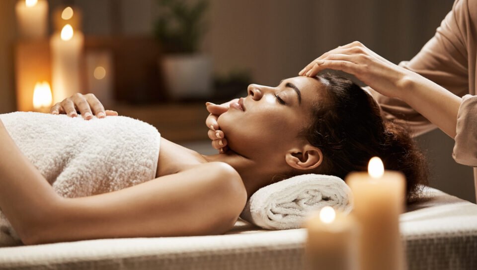 Attractive african girl enjoying face massage in spa salon. Closed eyes.