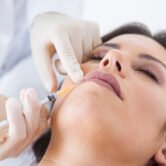 Portrait of beautiful young woman getting botox cosmetic injection in her face.