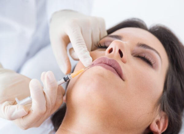 Portrait of beautiful young woman getting botox cosmetic injection in her face.
