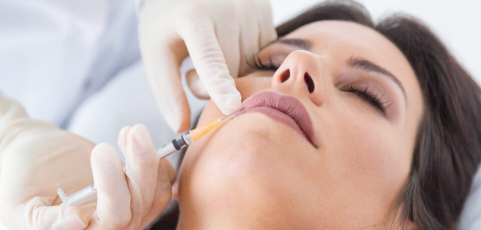 Portrait of beautiful young woman getting botox cosmetic injection in her face.